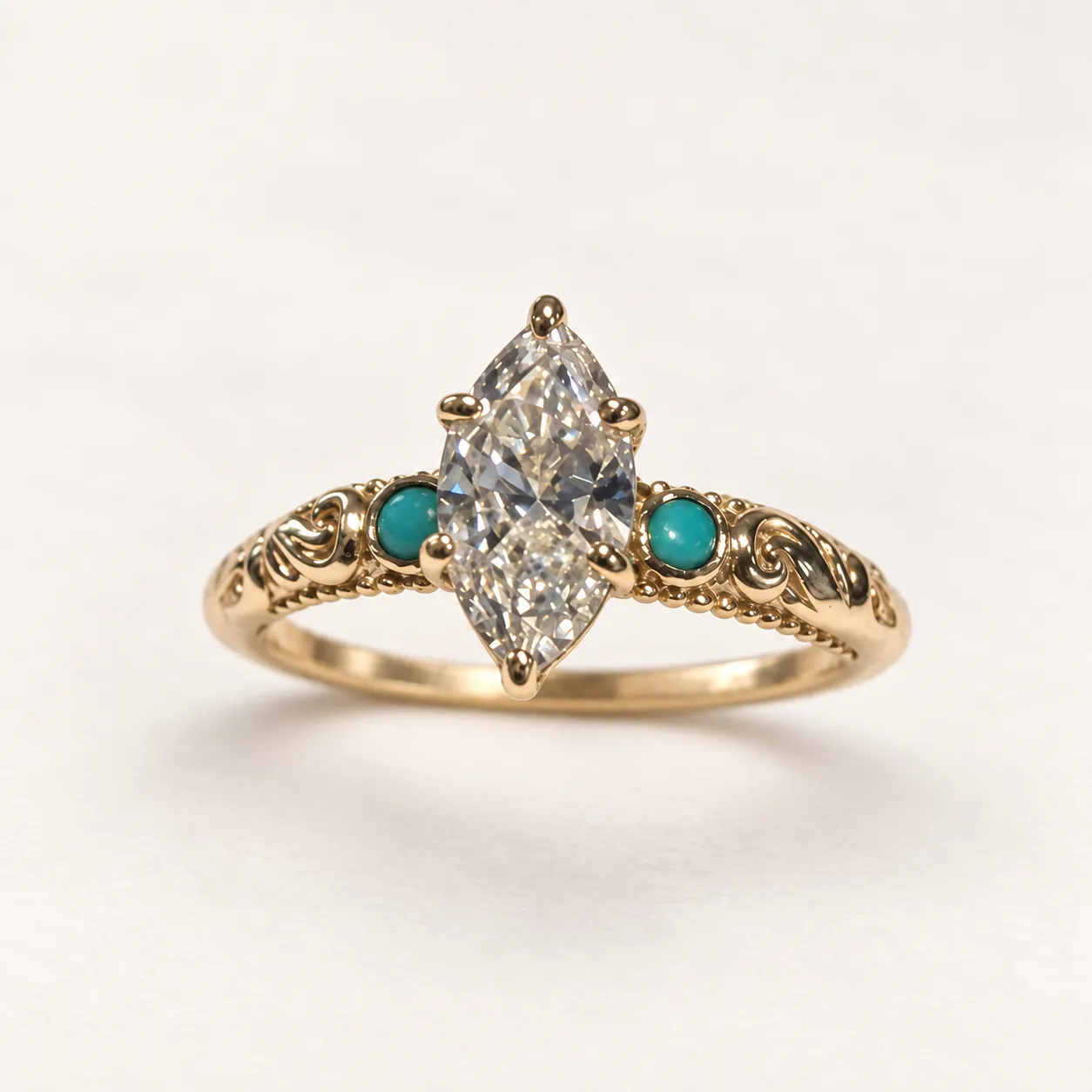 Face view of The Cindy in yellow gold with a marquise diamond, turquoise accents, and carved scrollwork.